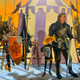 An unhelmeted knight stands to to a scrawny boy in a straw hat in front of a striped tent and weapons rack.